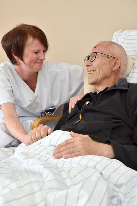 Pflegerin und Patient lächeln sich an.